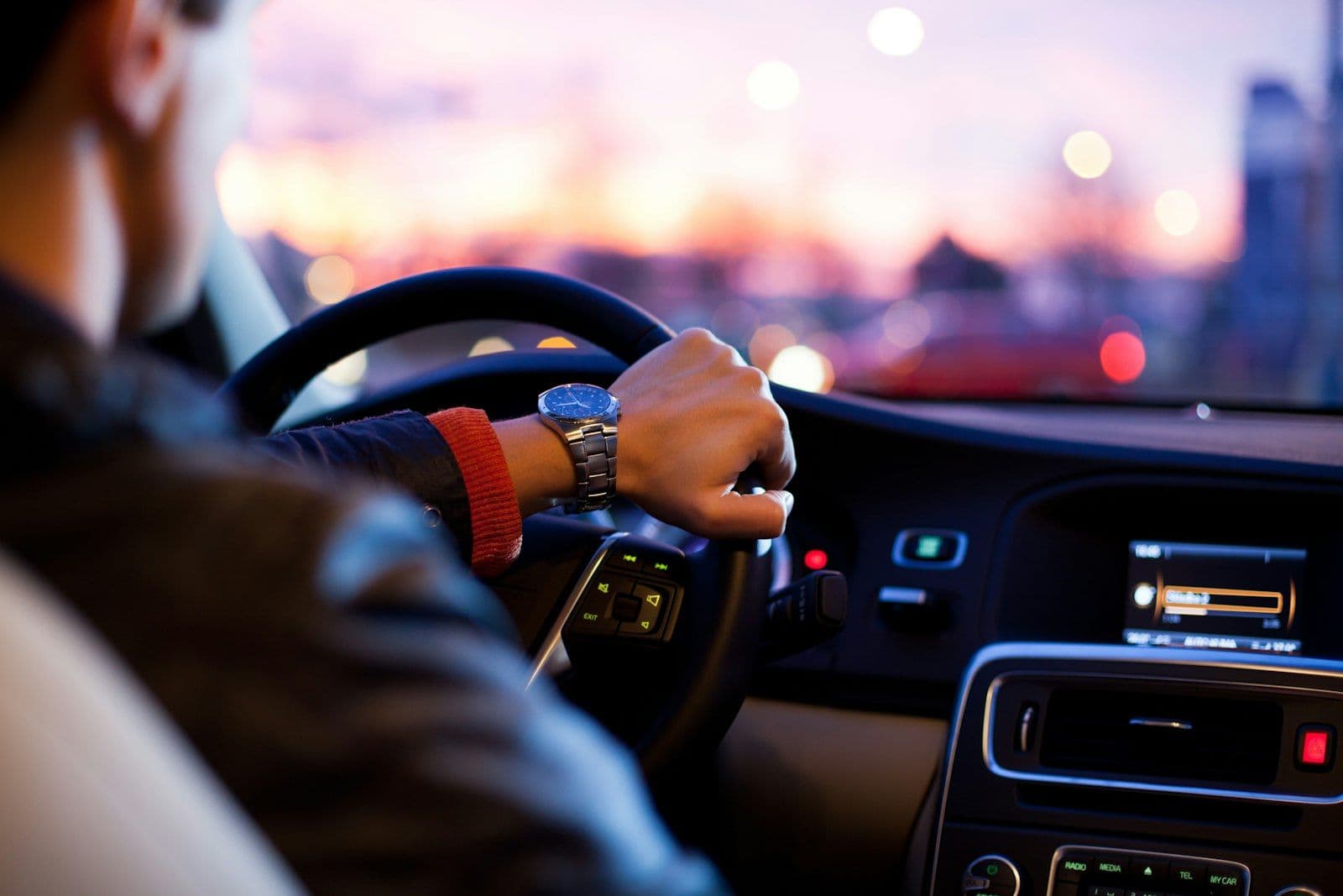 Hände am Lenkrad eines Autos in der Dämmerung
